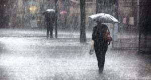 A woman walks down a street in the rain with an umbrella.