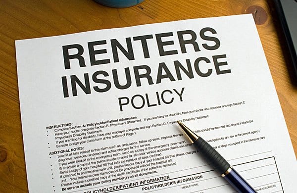 A renters insurance policy on a table with a pen.